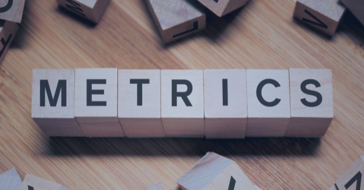 Recruiter Performance Metrics: Wooden letter blocks arranged to spell "METRICS" on a wooden surface, surrounded by scattered blocks with random letters. The image conveys a focus on data or measurement concepts.