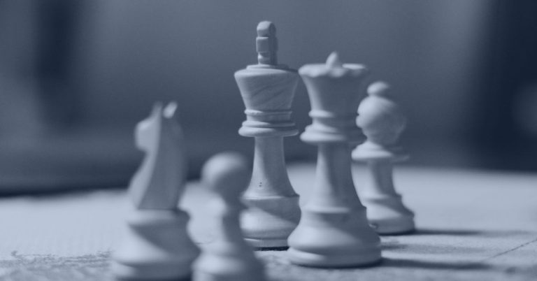 Intentional Recruiting Strategies: Close-up of wooden chess pieces on a board, with the king in focus and other pieces slightly blurred in the background.