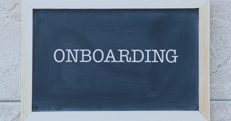 JobDiva Onboarding Automation: Chalkboard with the word 'ONBOARDING' written in white capital letters, framed with light wood, placed against a textured stone wall.