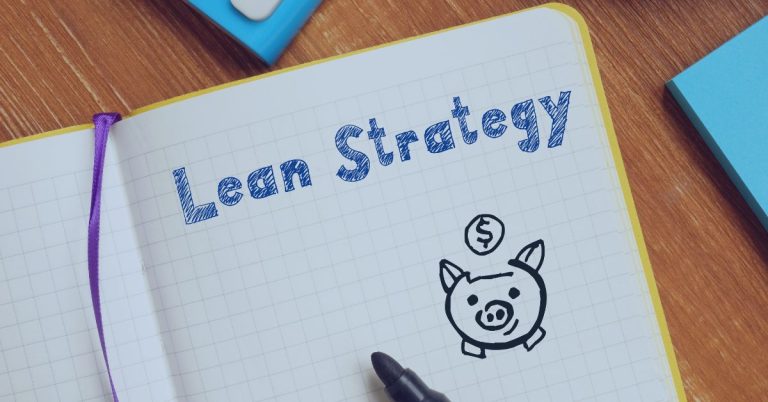 Lean Recruiting Strategies: Notebook with 'Lean Strategy' written in blue ink on graph paper, accompanied by a hand-drawn piggy bank illustration with a coin dropping in, symbolizing cost-effective planning.