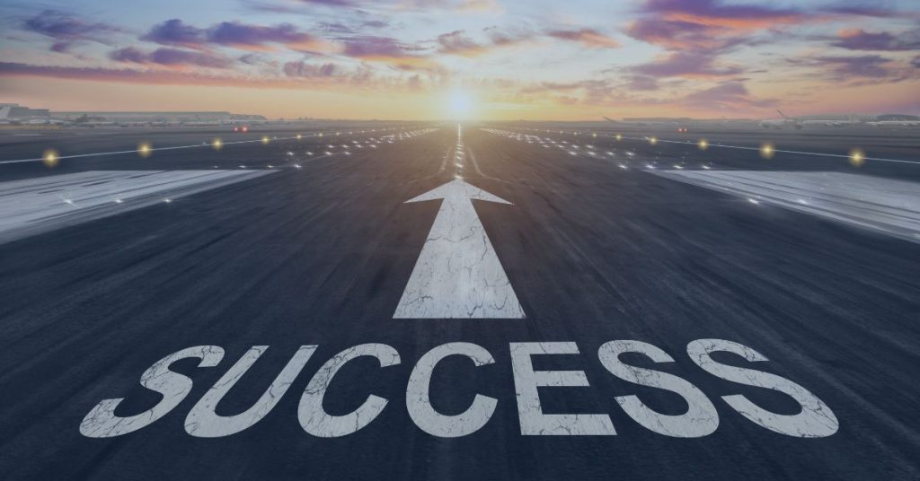 Staffing Agency Success: Runway at sunrise with the word 'SUCCESS' painted on the ground and a large arrow pointing toward the horizon, symbolizing progress and achievement.